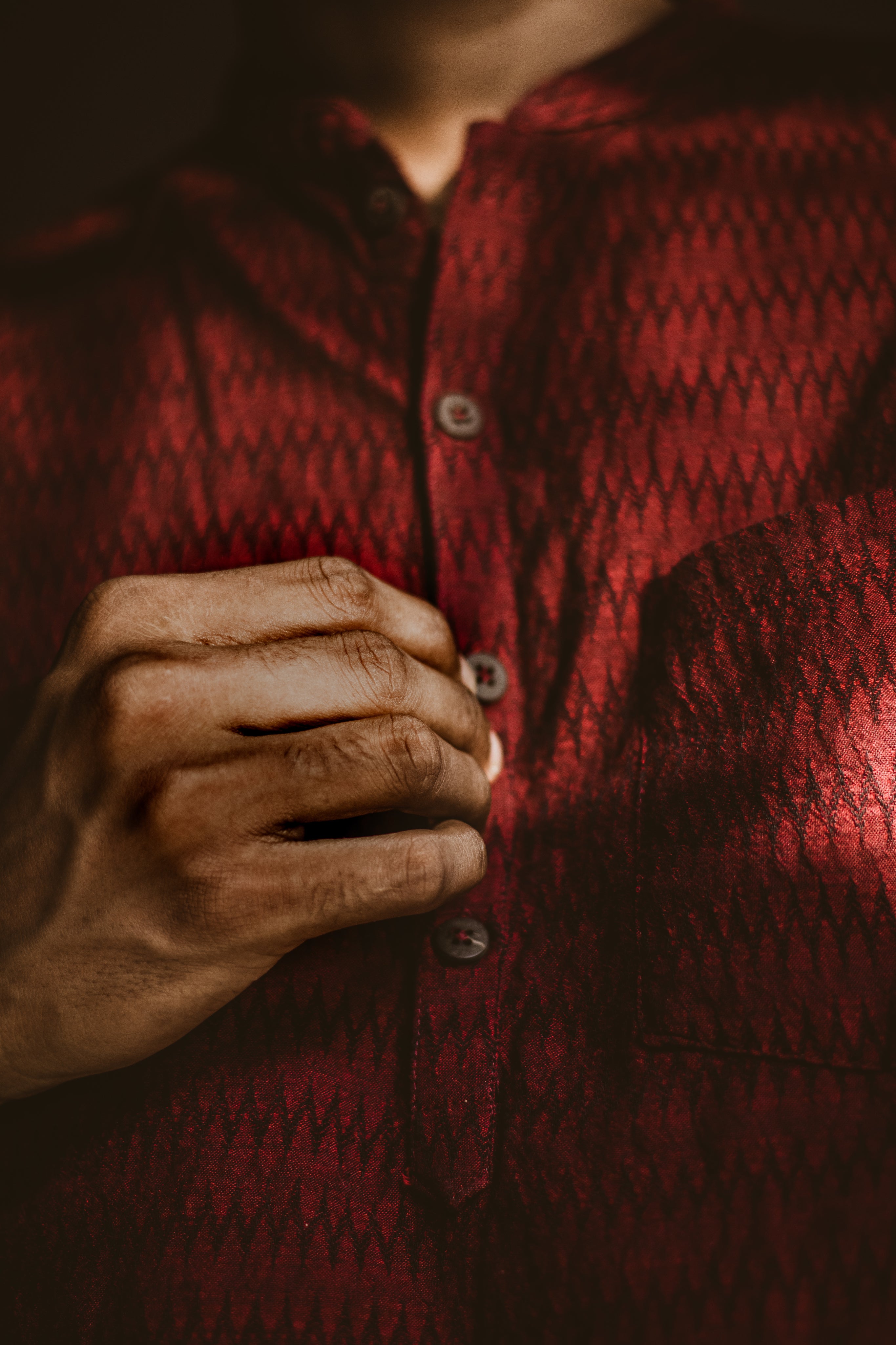 man-buttoning-a-dark-red-shirt.jpg